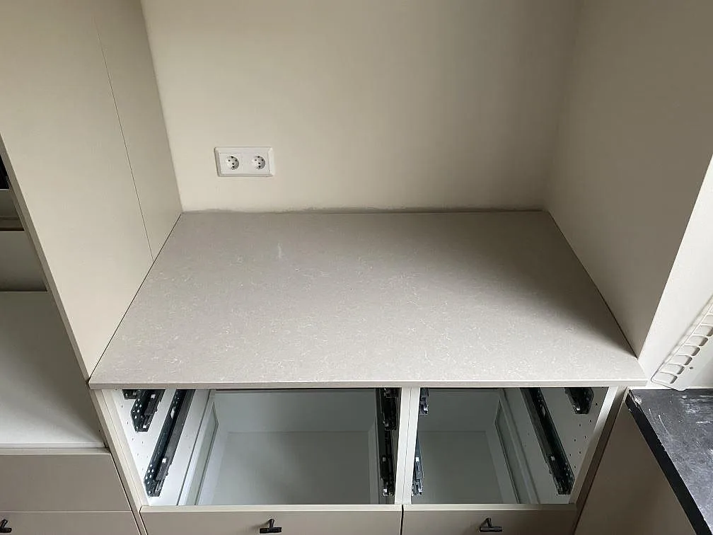 Rak bänkdel i polerad Technistone Noble Ivory White i en nisch med öppna köksstommar och ljus kvartskomposityta i Malmö.