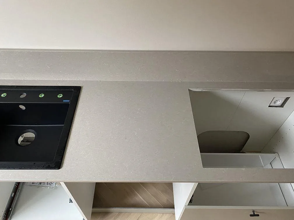 Detalj av Technistone Noble Ivory White med svart diskho, större urtag och ljus polerad arbetsyta i ett Malmö-kök.