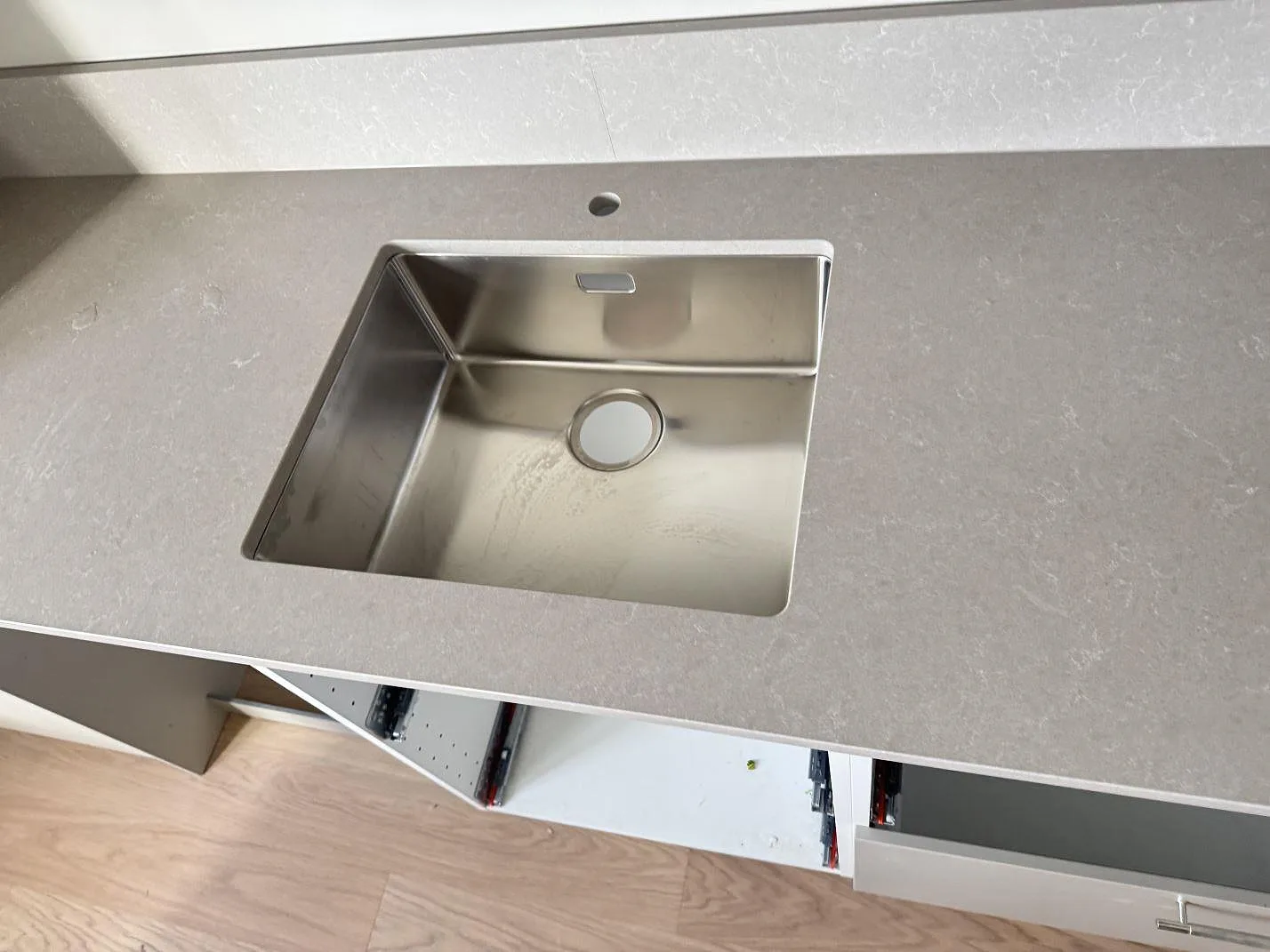 Närbild på polerad Technistone Noble Ivory White som bänkskiva runt en rostfri diskho i ett kök i Malmö.