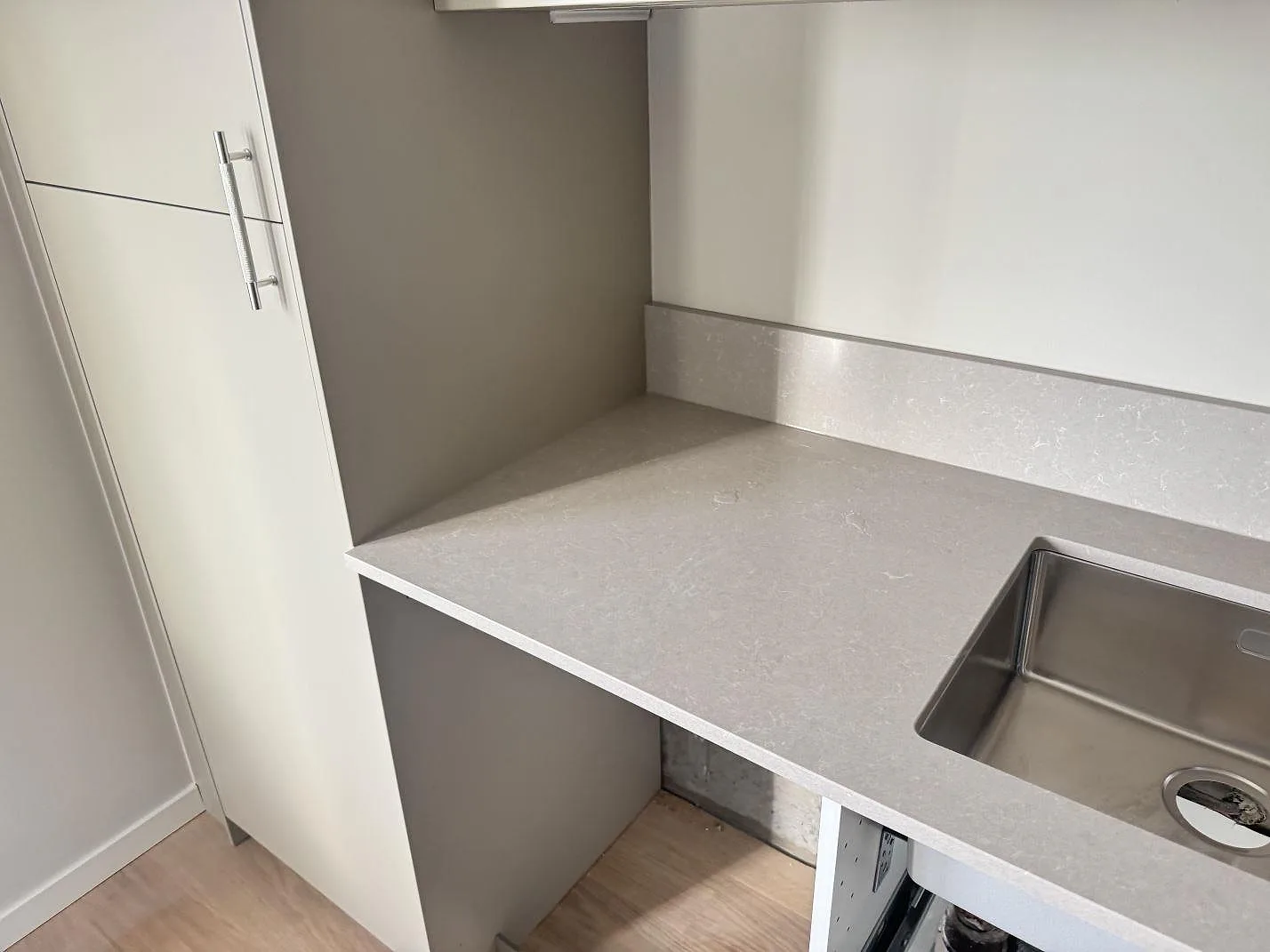 Sidovy av köksbänkskiva i polerad Technistone Noble Ivory White med stänkskydd och synlig rostfri diskho i Malmö.