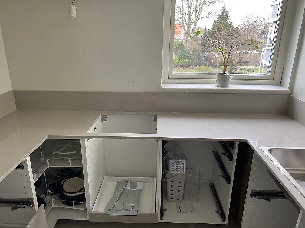 Köksbänkskiva i ljus Technistone Noble Ivory White, polerad kvartskomposit, under fönster med urtag för häll och låg stänkkant i Malmö.