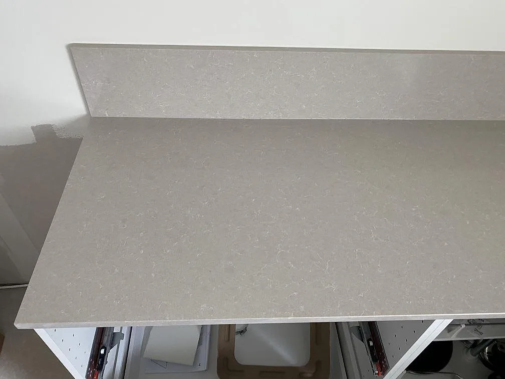 Detalj av polerad Technistone Noble Ivory White på köksbänk med uppvikt stänkkant och ljus spräcklig struktur i Malmö.