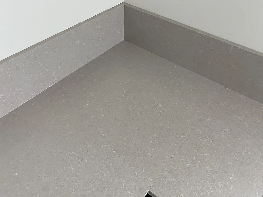 Närbild av hörn och stänkkant i polerad Technistone Noble Ivory White, ljus kvartskomposit på köksbänkskiva i Malmö.
