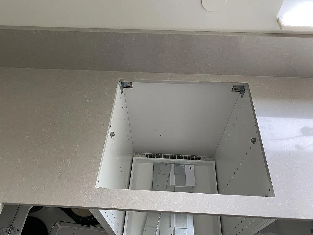 Urtag för häll i en polerad köksbänkskiva av Technistone Noble Ivory White med låg stänkkant under fönster i Malmö.