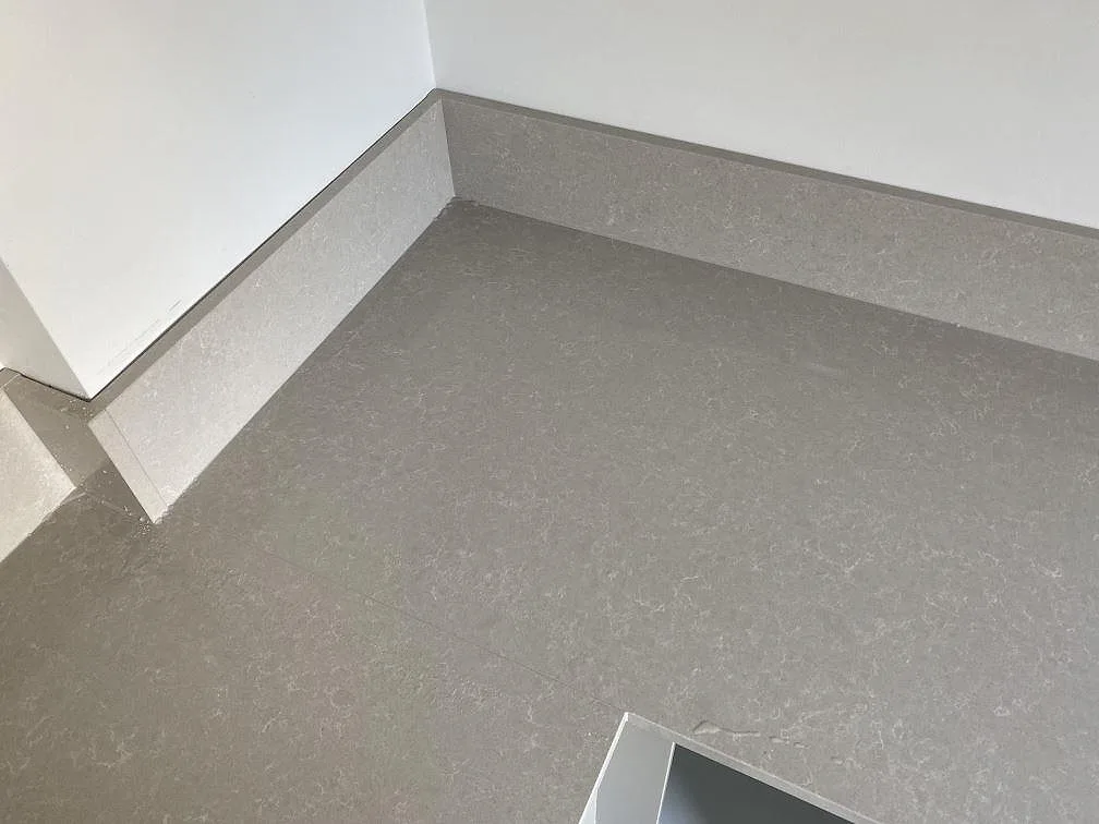 Hörndetalj på köksbänkskiva i polerad Technistone Noble Ivory White kvartskomposit med uppvikt stänkkant i Malmö.