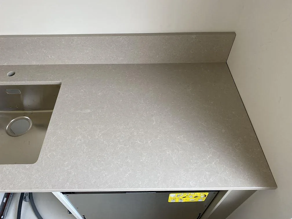 Diskhonära arbetsyta i polerad Technistone Noble Ivory White kvartskomposit med låg stänkkant och ljus ådring i Malmö.