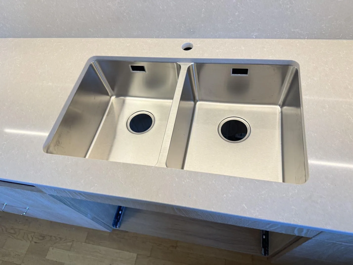 Närbild på rostfri dubbelho monterad i polerad köksbänkskiva av Technistone Noble Ivory White komposit i Malmö.