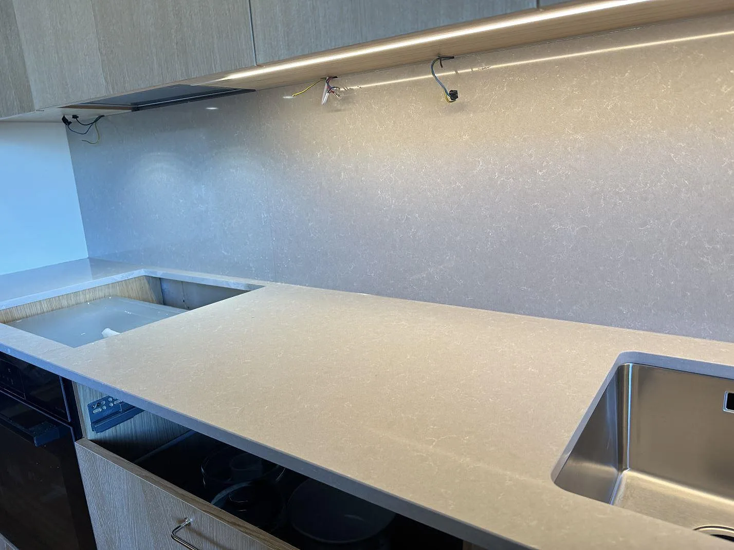 Köksbänkskiva i polerad Technistone Noble Ivory White komposit med hällurtag, rostfri diskho och fullhögt stänkskydd i ett kök i Malmö.