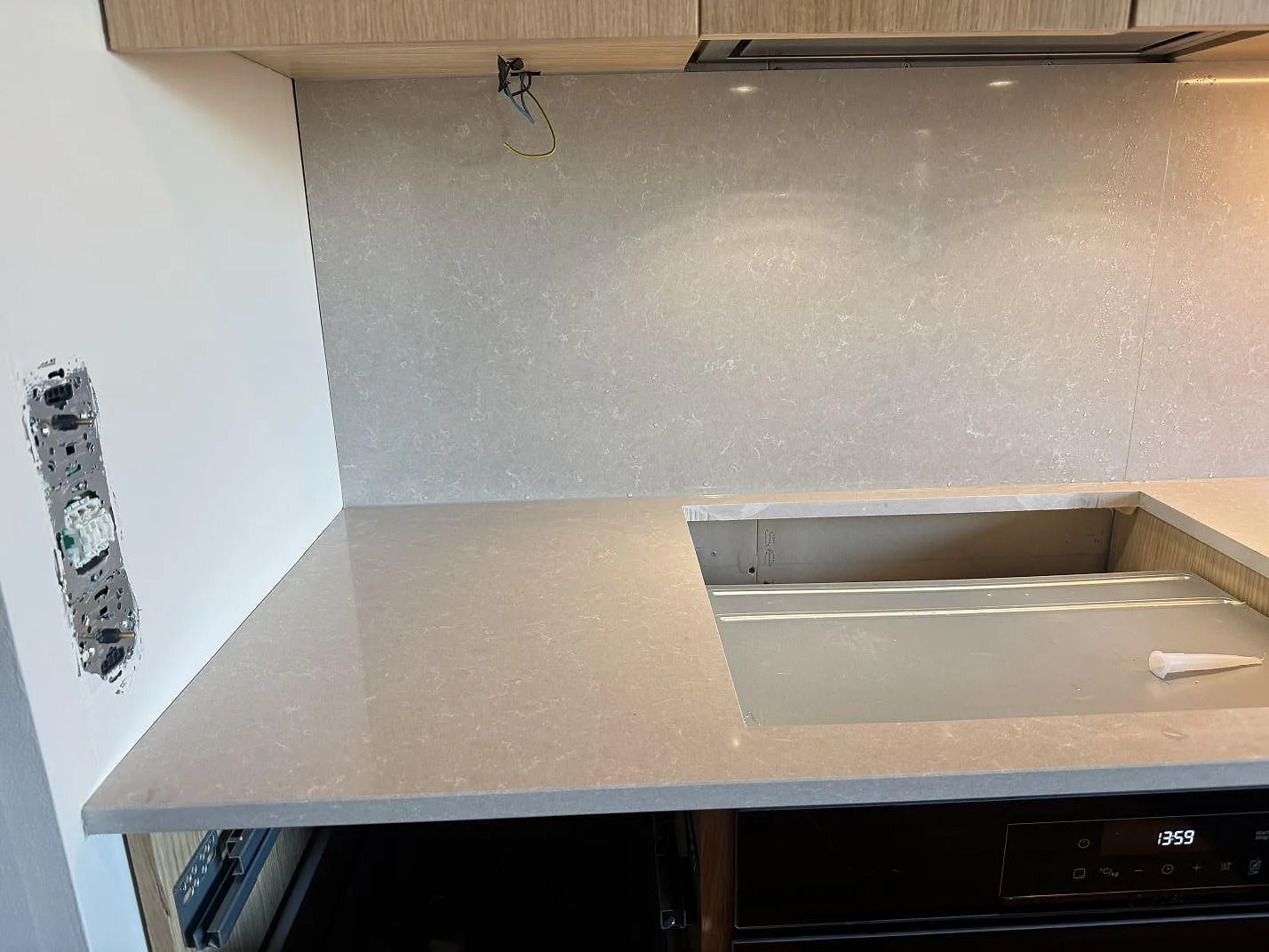 Köksbänk i polerad Technistone Noble Ivory White komposit med hällöppning, stänkpanel och synliga monteringsdetaljer i Malmö.