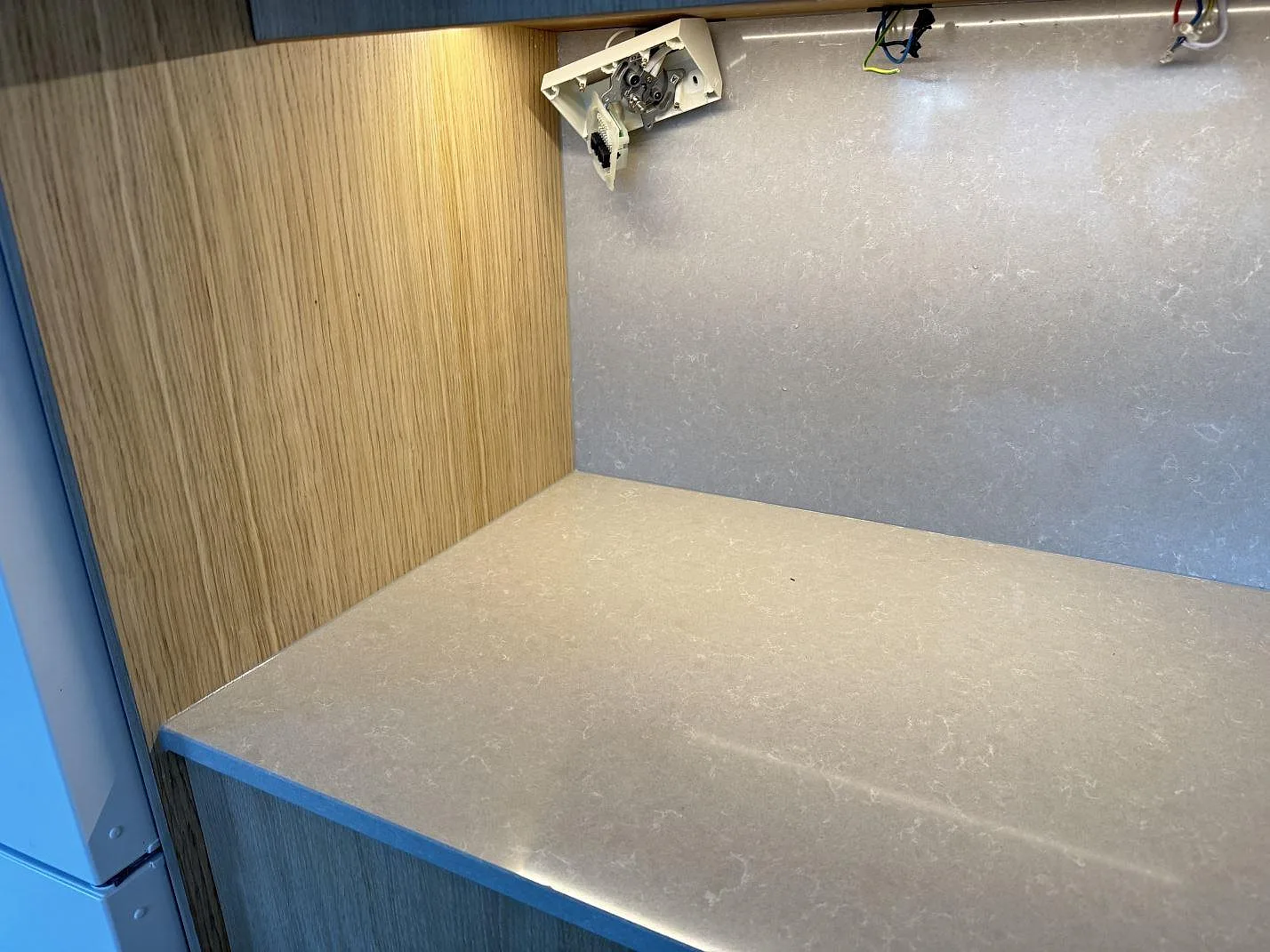 Sidodel av köksbänkskiva i polerad Technistone Noble Ivory White komposit med matchande stänkpanel och träskåp i Malmö.