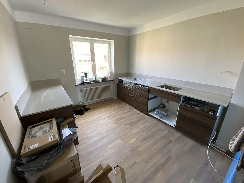 Köksbänkskiva i Technistone Noble Ivory White, polerad ljus kvartskomposit, med uppvikt stänkkant och diskho i ett kök under montering i Malmö.