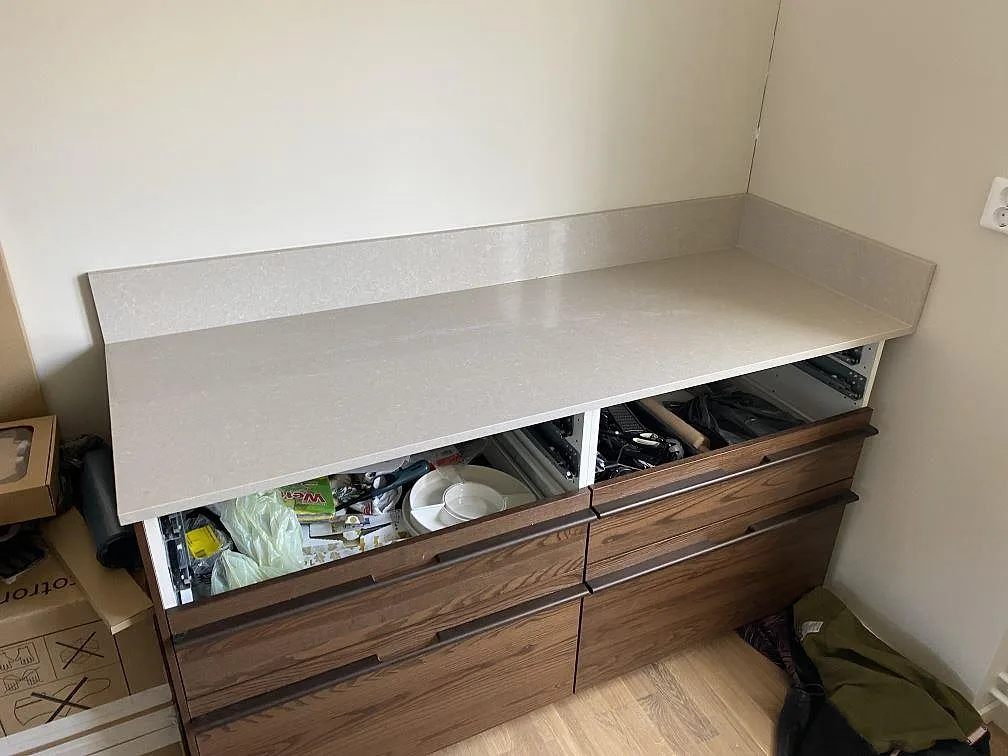 Sidobänk i Technistone Noble Ivory White, polerad kvartskomposit, med uppvikt stänkkant ovanpå träinredning i Malmö.