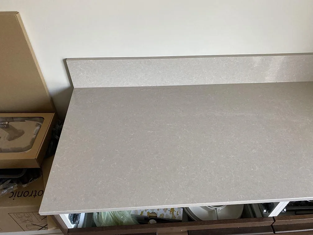 Yta och uppvikt stänkkant i Technistone Noble Ivory White, polerad ljus kvartskomposit, på en köksbänk i Malmö.