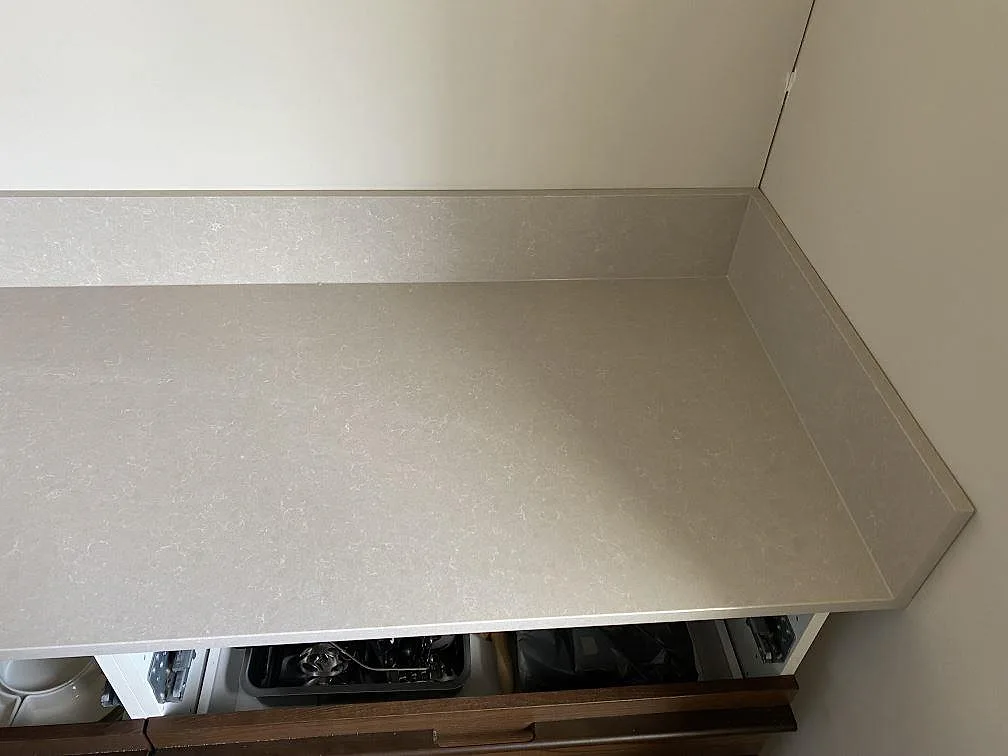 Hörnsektion av köksbänkskiva i Technistone Noble Ivory White, polerad kvartskomposit, med sidostänkkant i Malmö.