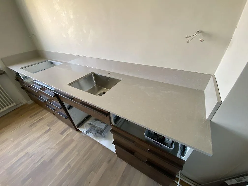 Polerad köksbänkskiva i Technistone Noble Ivory White med diskho, hällurtag och uppvikt stänkkant i ett kök i Malmö.