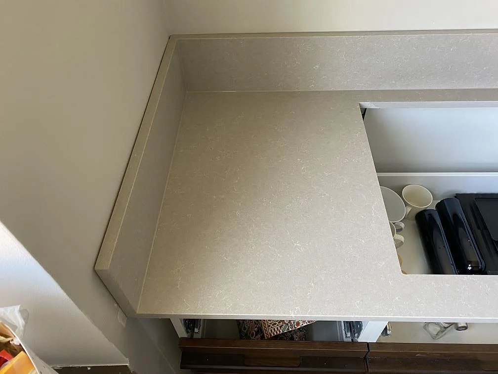 Närbild på polerad Technistone Noble Ivory White med hällurtag, ljus kvartskomposit och sidokant mot vägg i ett kök i Malmö.