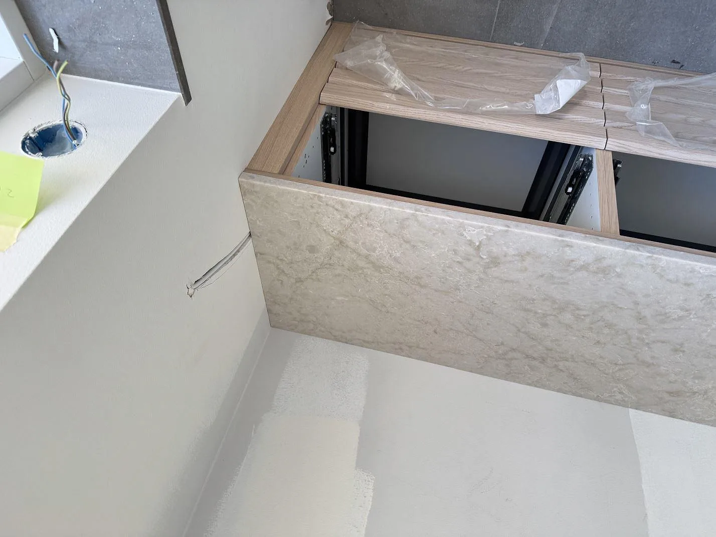 Polerad Technistone Noble Ivory White som frontpanel vid trästommar och vägg under montering i Malmö.