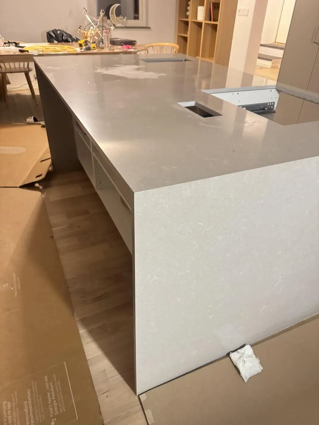 Stor köksö i polerad vit Technistone Noble Ivory White komposit i ett öppet rum under montering i Malmö.
