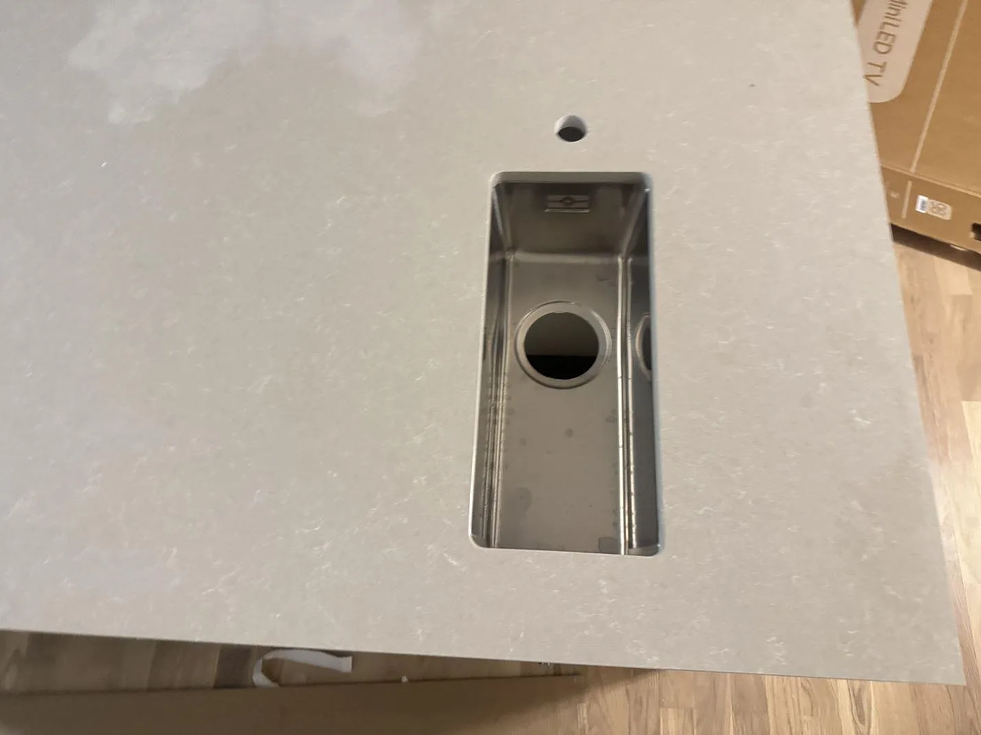 Närbild på liten underlimmad rostfri diskho och blandarhål i polerad Technistone Noble Ivory White köksbänkskiva i Malmö.