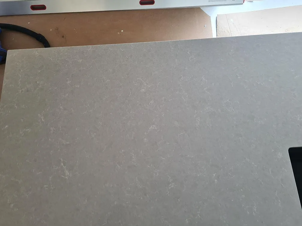 Närbild av den ljusa mönstringen i polerad Technistone Noble Ivory White på installerad köksbänkskiva i Ösmo.