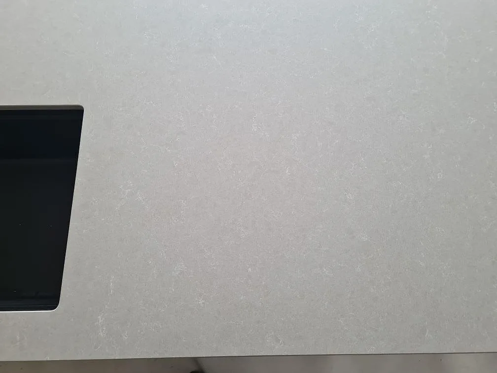 Ytdetalj av polerad Technistone Noble Ivory White kvartskomposit vid den svarta diskhon i köket i Ösmo.