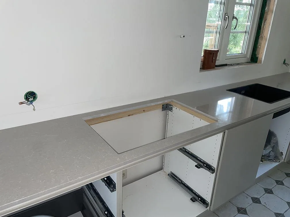 Köksbänkskiva i polerad Technistone Noble Ivory White komposit med synliga ursågningar i ett kök under montering i Östhammar.