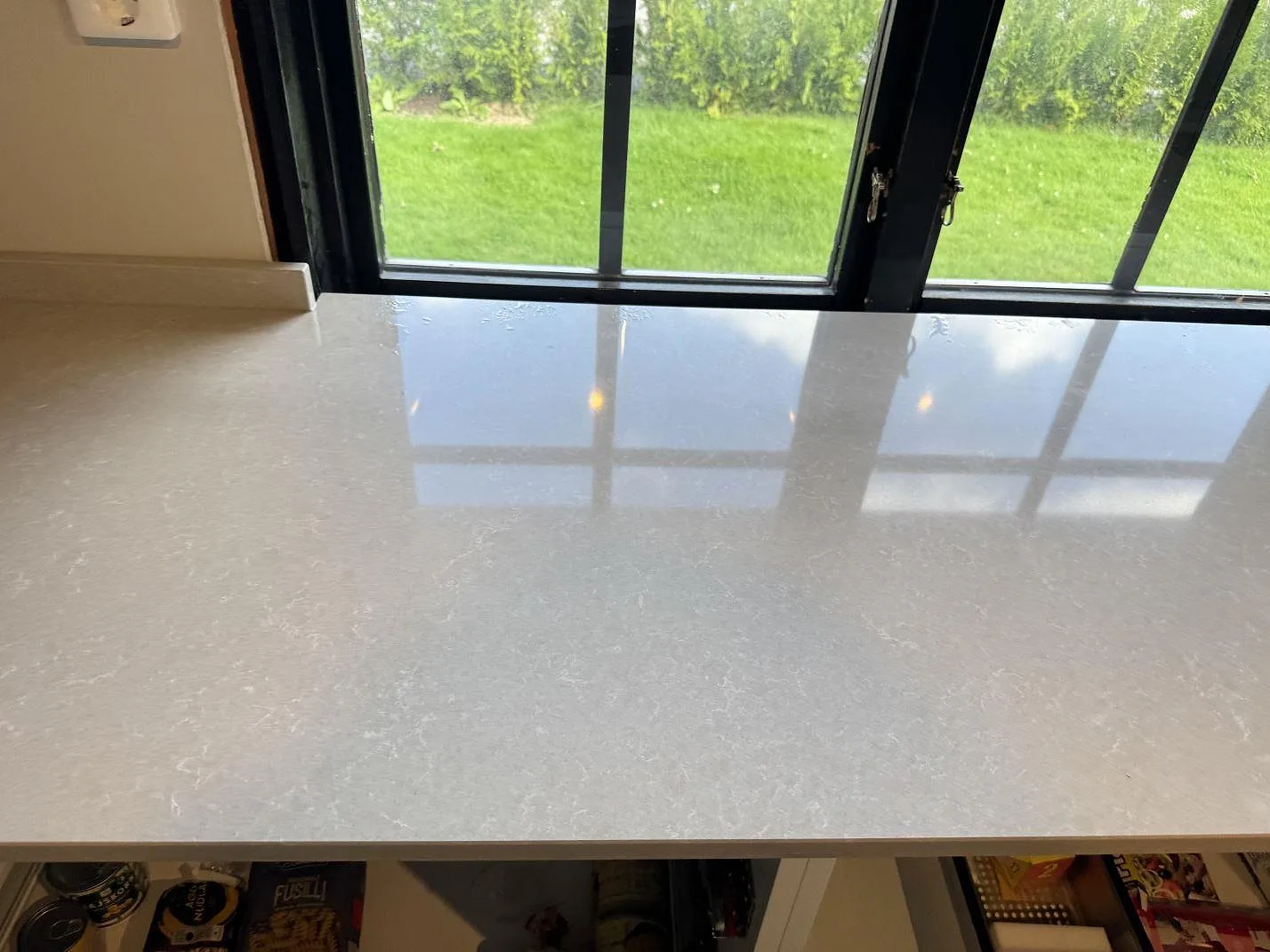 Blankpolerad Technistone Noble Ivory White som köksbänk under fönster med tydliga reflexer i Oskarström.