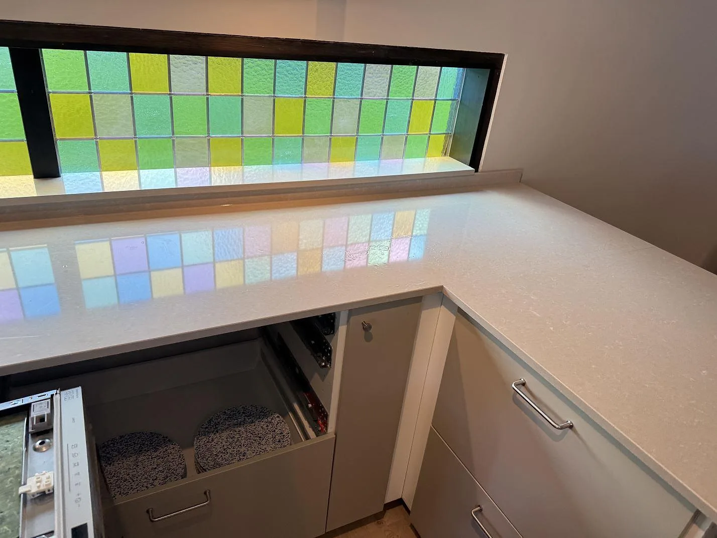 Polerad Technistone Noble Ivory White på köksbänk med låg uppvikt stänkkant och öppna köksstommar i Oskarström.