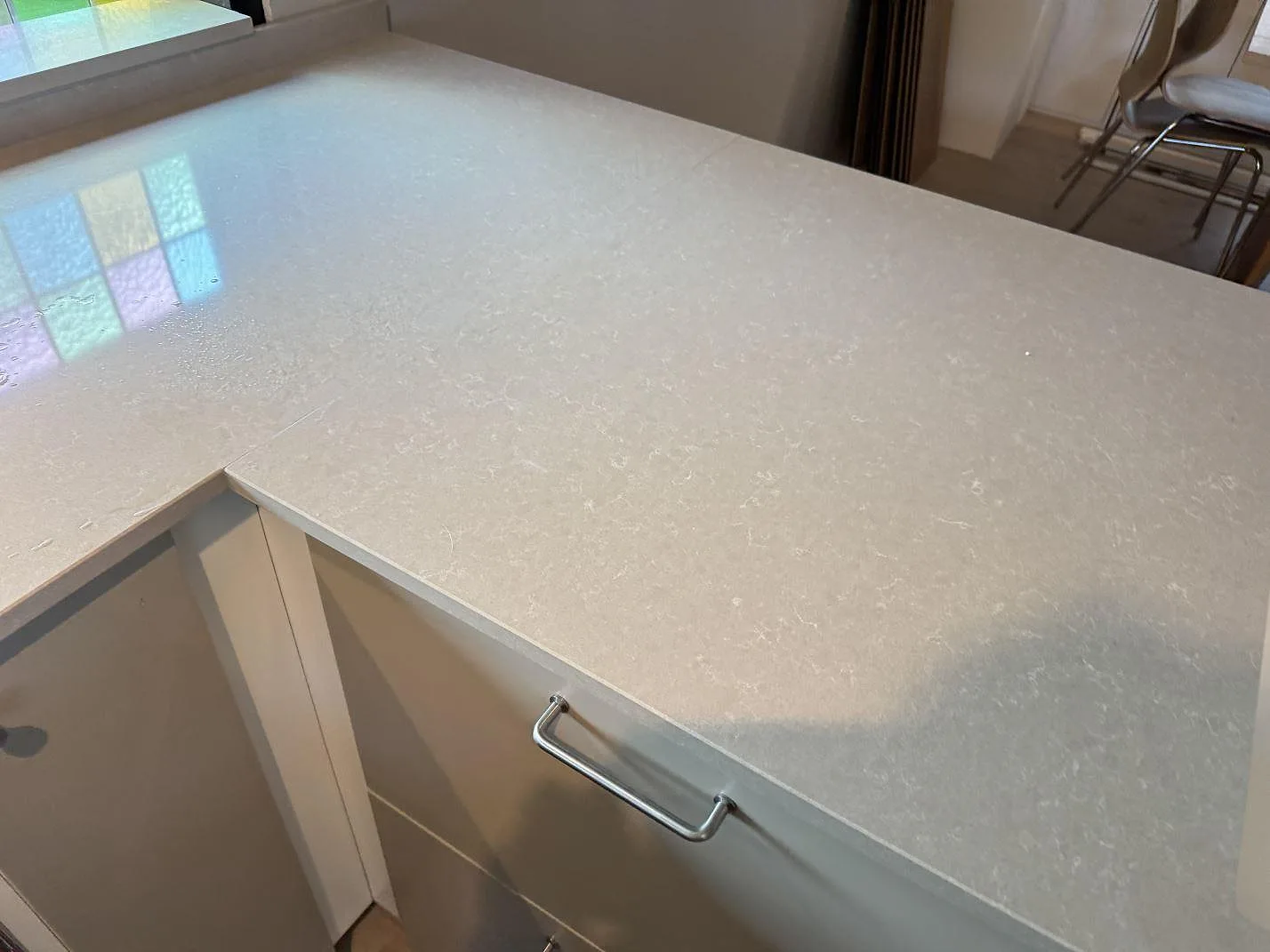 Närbild av 20 mm Technistone Noble Ivory White, polerad kvartskomposit, på köksbänk med synlig ljus ådring i Oskarström.