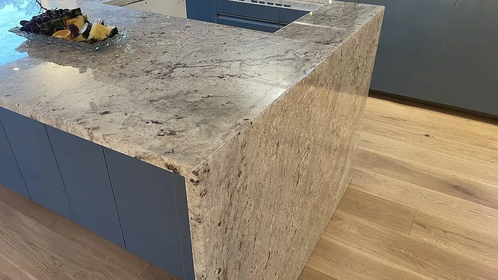 Närbild av polerad Technistone Noble Ivory White på köksö med neddragen sida och ljus ådring i Oskarström.