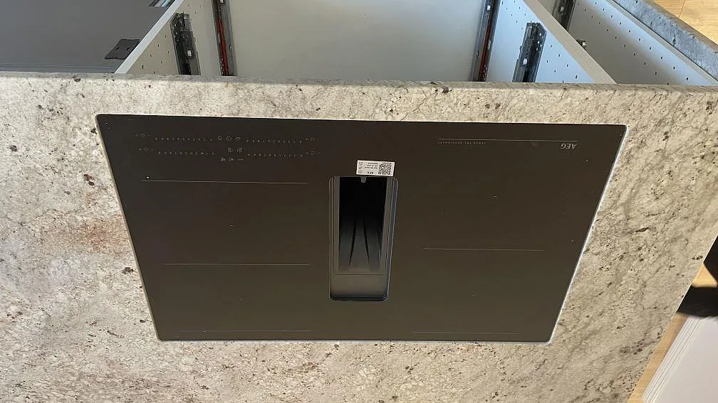 Svart häll monterad i köksbänkskiva av polerad Technistone Noble Ivory White i Oskarström.