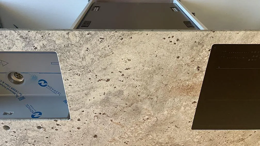 Polerad kvartskomposit Technistone Noble Ivory White mellan underlimmad diskho och häll på köksö i Oskarström.