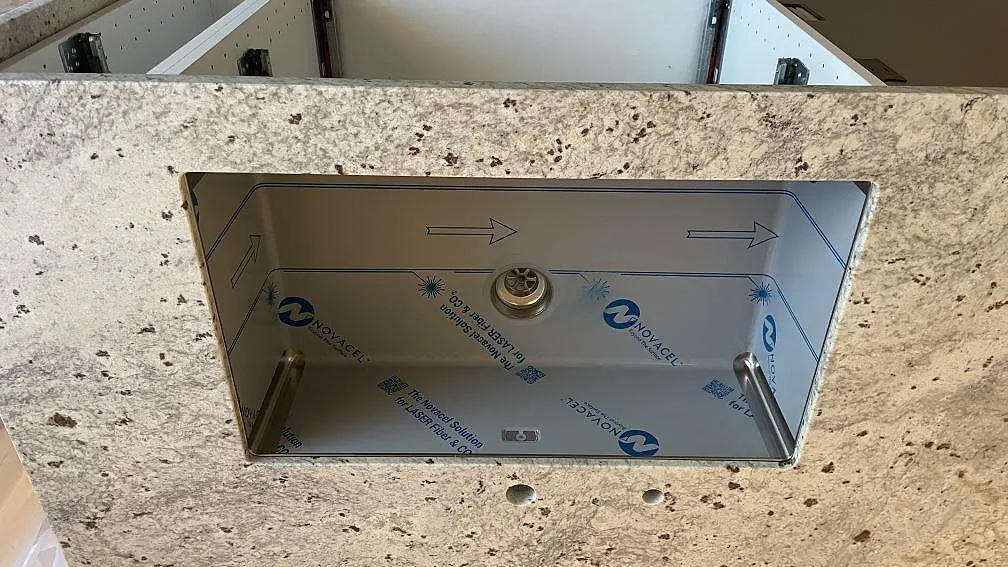 Underlimmad rostfri diskho i polerad Technistone Noble Ivory White med kranhål i kök i Oskarström.