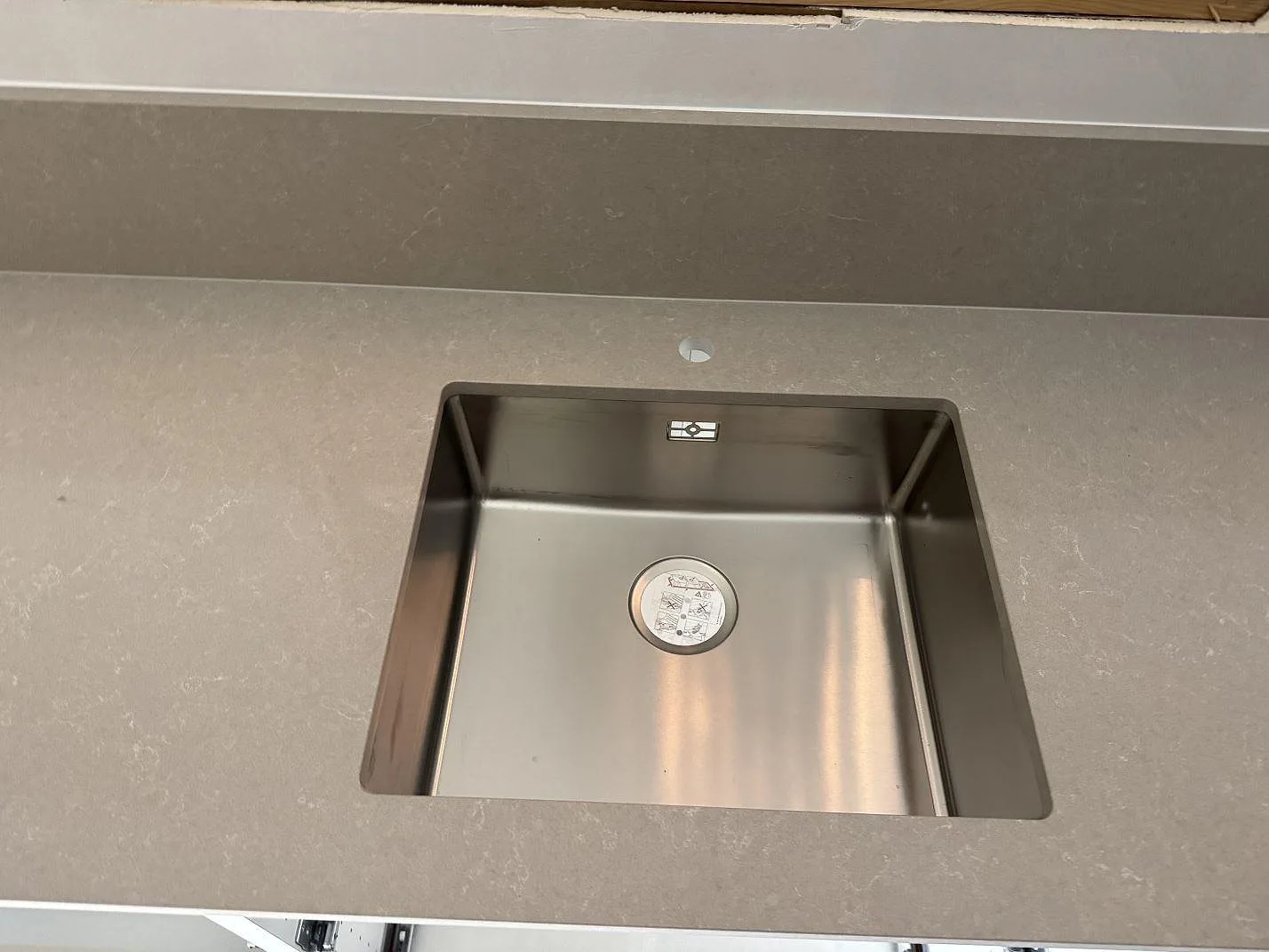 Närbild på underlimmad rostfri diskho i polerad Technistone Noble Ivory White med stänkkant i Ronneby.