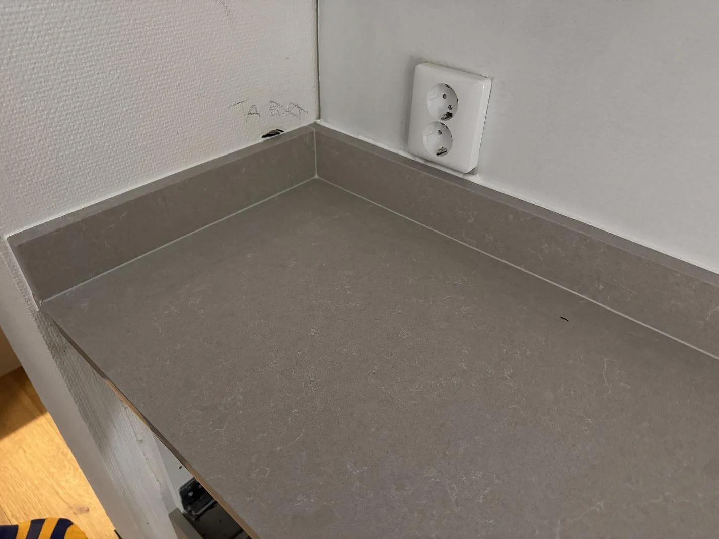 Detalj av polerad Technistone Noble Ivory White som köksbänkskiva med uppvikt stänkkant i Ronneby.