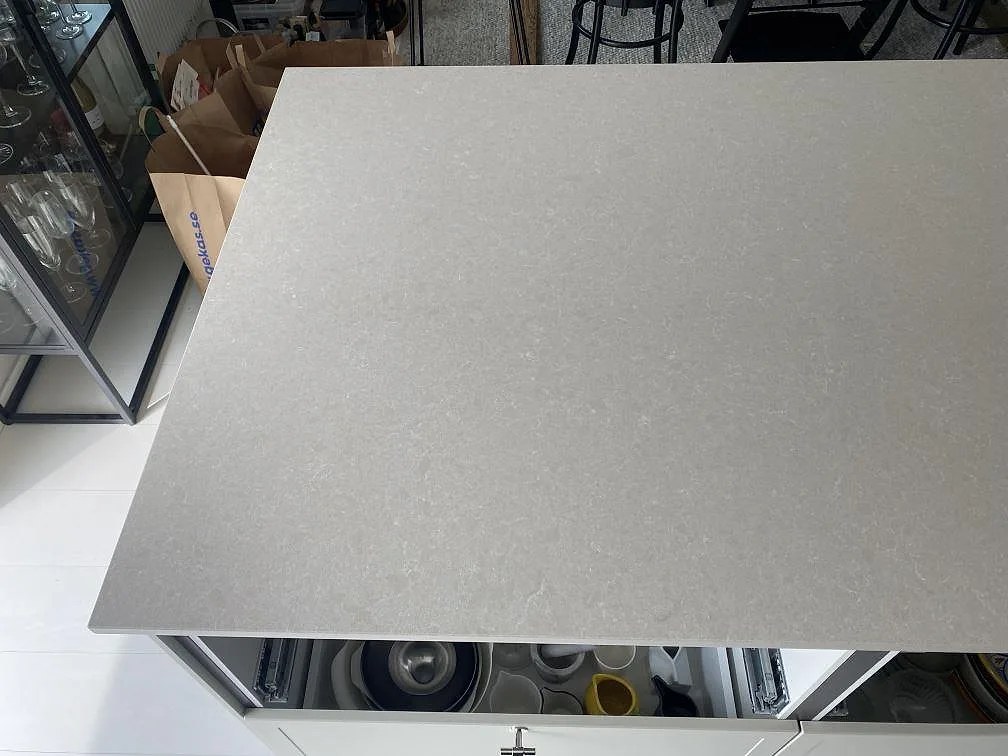 Köksö i polerad Technistone Noble Ivory White komposit med ljus ådring och rak kant i ett kök i Simrishamn.