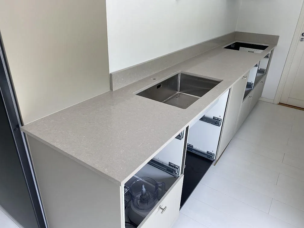 Rak köksbänkskiva i polerad Technistone Noble Ivory White med rostfri diskho, hällöppning och låg stänkkant i Simrishamn.