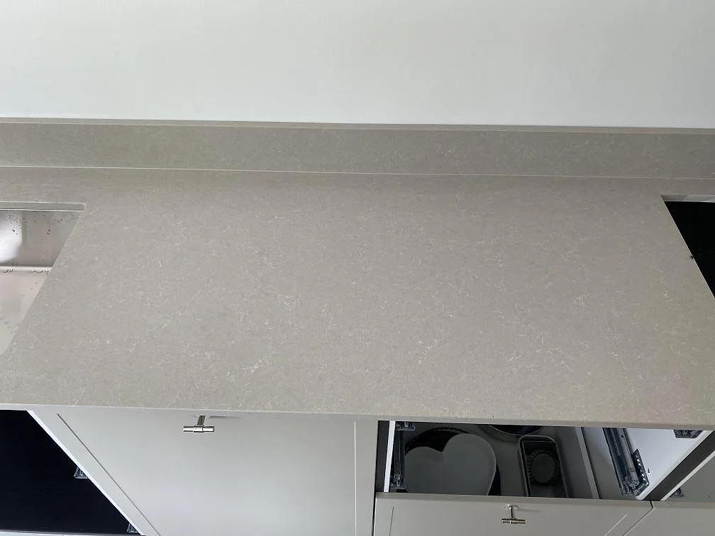Detalj av polerad Technistone Noble Ivory White mellan diskho och hällöppning, med låg stänkkant i köket i Simrishamn.