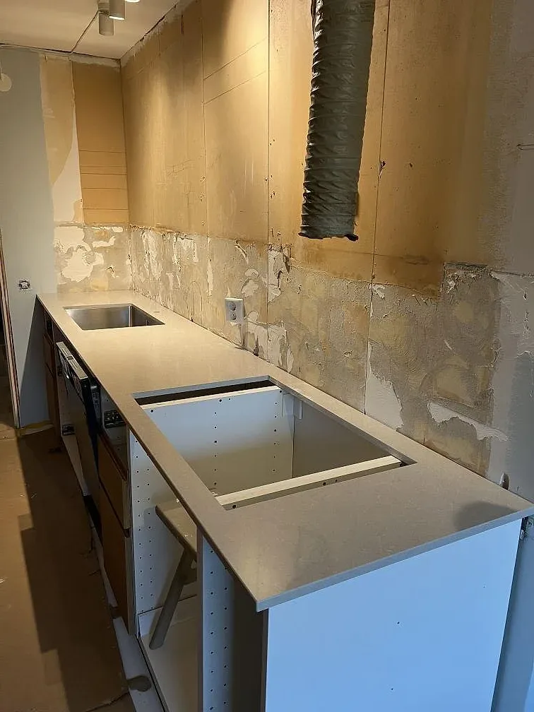 Montering av köksbänkskiva i Technistone Noble Ivory White, polerad 20 mm komposit, med utskurna öppningar i ett kök i Sköndal.