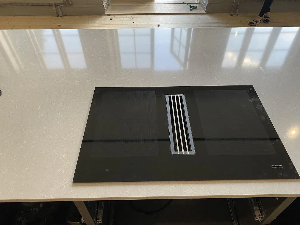 Miele induktionshäll infälld i polerad bänkskiva av Technistone Noble Ivory White i ett kök i Staffanstorp.