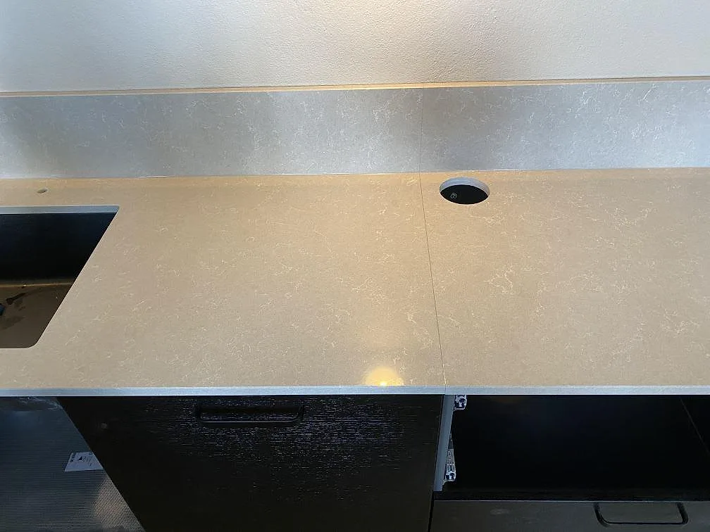 Köksbänkskiva i Technistone Noble Ivory White med underlimmad diskho och hål för köksblandare i ett kök i Staffanstorp.