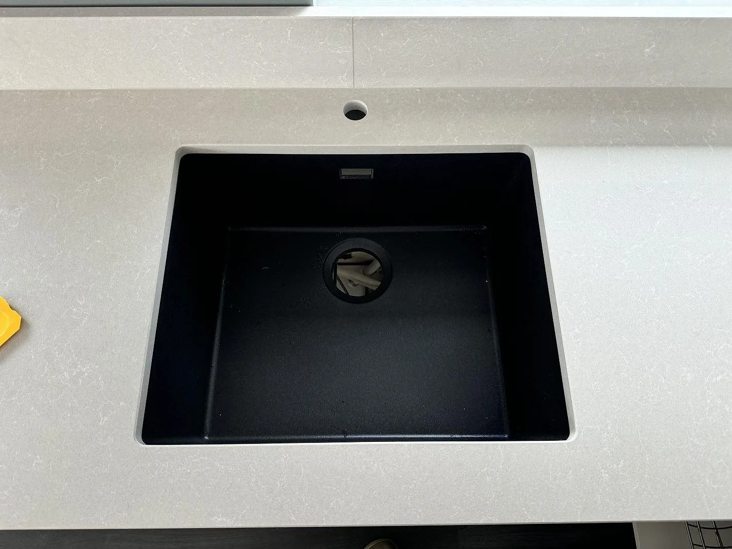 Detalj av svart diskho i köksbänkskiva av Technistone Noble Ivory White, polerad kvartskomposit, i Staffanstorp.