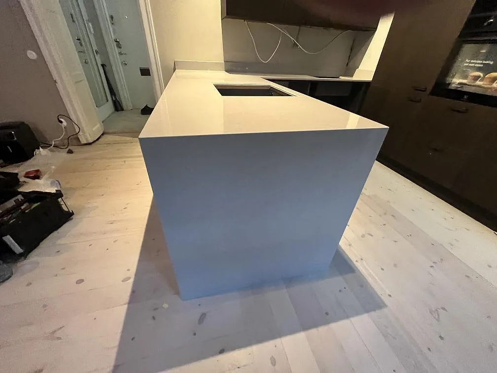 Närbild av köksö i Technistone Noble Ivory White, polerad vit komposit med mjuk ådring och urtag i ett kök i Stockholm.