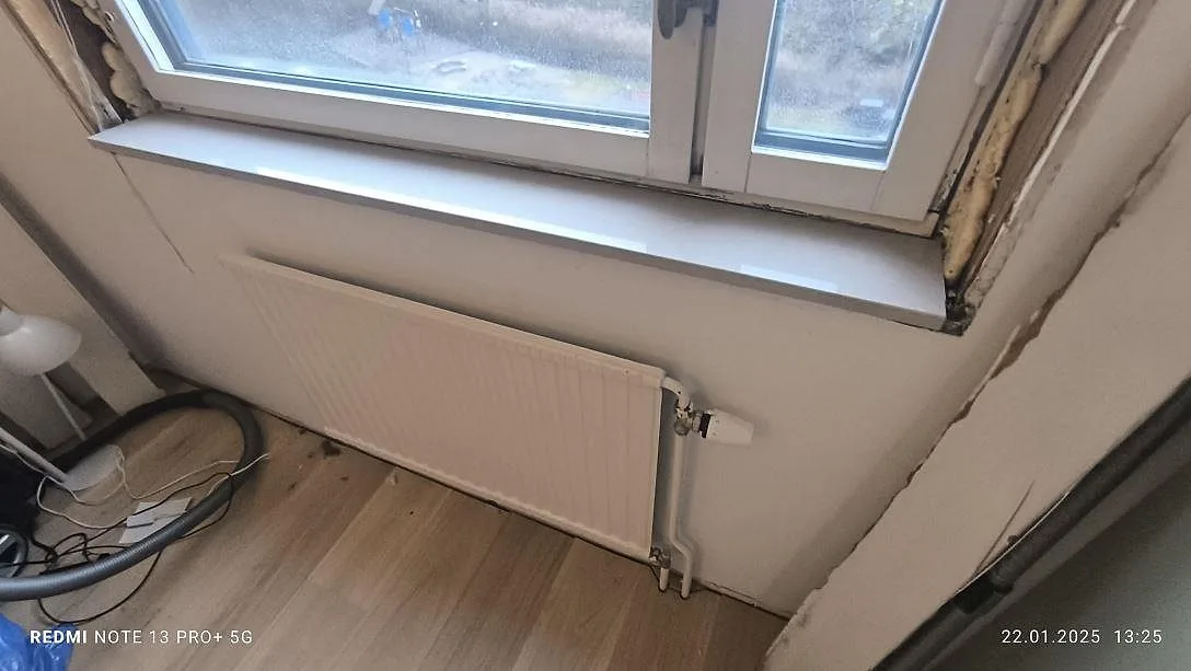 Närbild av fönsterbänk i polerad Technistone Noble Ivory White, ljus komposit ovanför radiator i Stockholm.