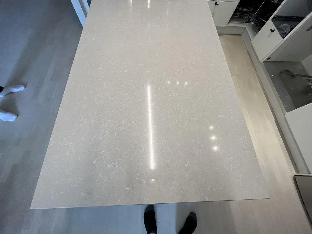 Närbild ovanifrån av den polerade Technistone Noble Ivory White köksön med ljus mönstring i Stockholm.