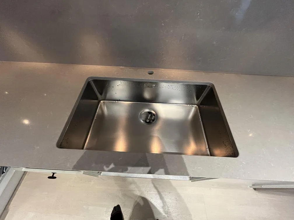 Underlimmad rostfri diskho i en polerad Technistone Noble Ivory White bänkskiva med stänkskydd i Stockholm.