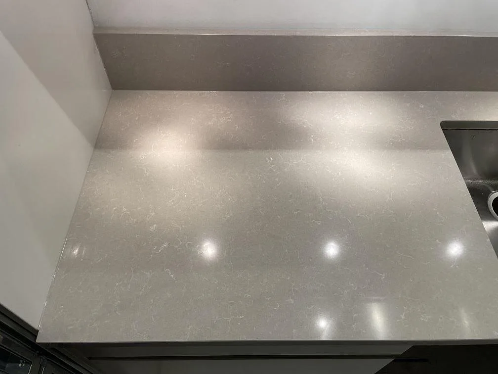 Detaljbild av polerad Technistone Noble Ivory White i komposit med ljus ådring och stänkkant vid diskhon i Stockholm.