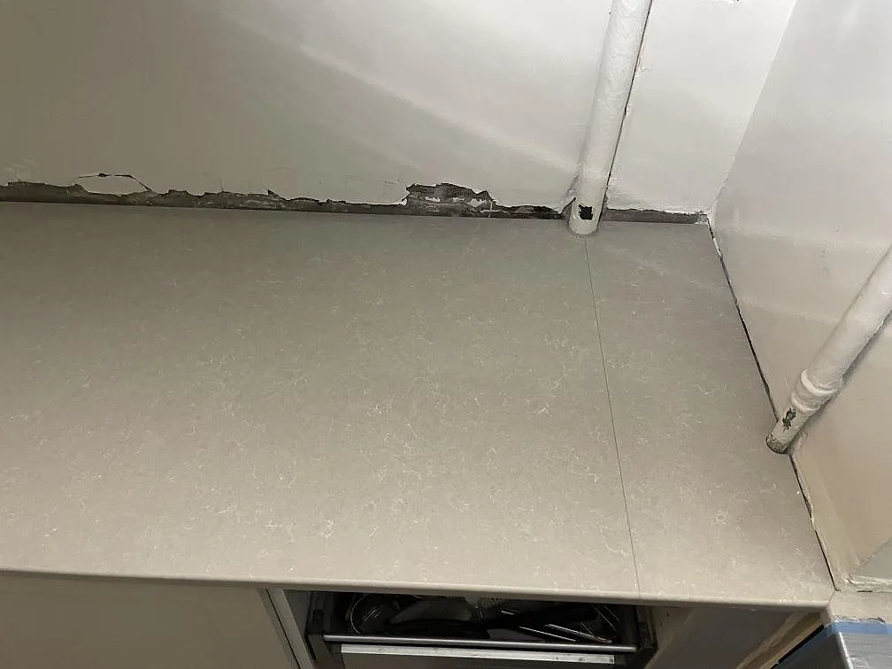 Närbild på den polerade ytan med mjuk ådring i Technistone Noble Ivory White komposit på en köksbänk i Stockholm.