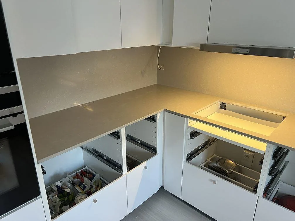 Närmare vy av köksbänkskiva i polerad Technistone Noble Ivory White, kvartskomposit, med stänkskydd och öppna köksstommar i Sturefors.