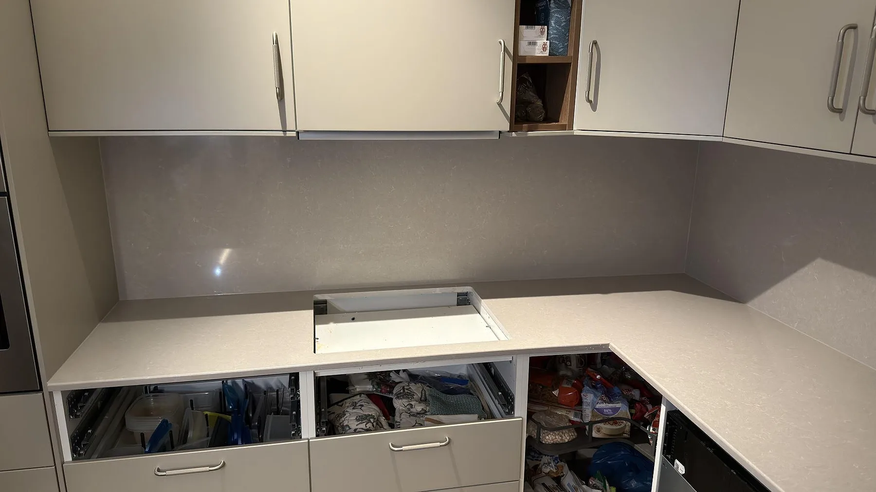 Köksbänkskiva i varmvit Technistone Noble Ivory White, polerad, med urtagning för induktionshäll och uppvikt stänkskydd i ett kök i Sundbyberg.